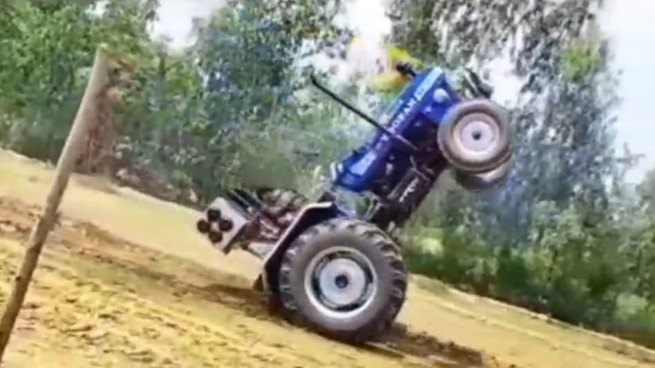 The young man was stunting the wheel in front of the tractor The young man was stunting the wheel in front of the tractor