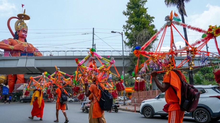 Kanwariyas walk past the statue of Lord Hanuman at Jhandewala area (File Photo-PTI)