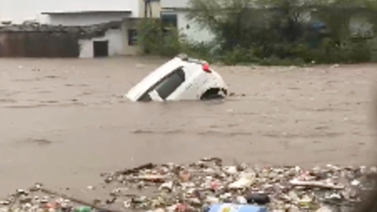 बारिश के पानी में बहती एक कार.