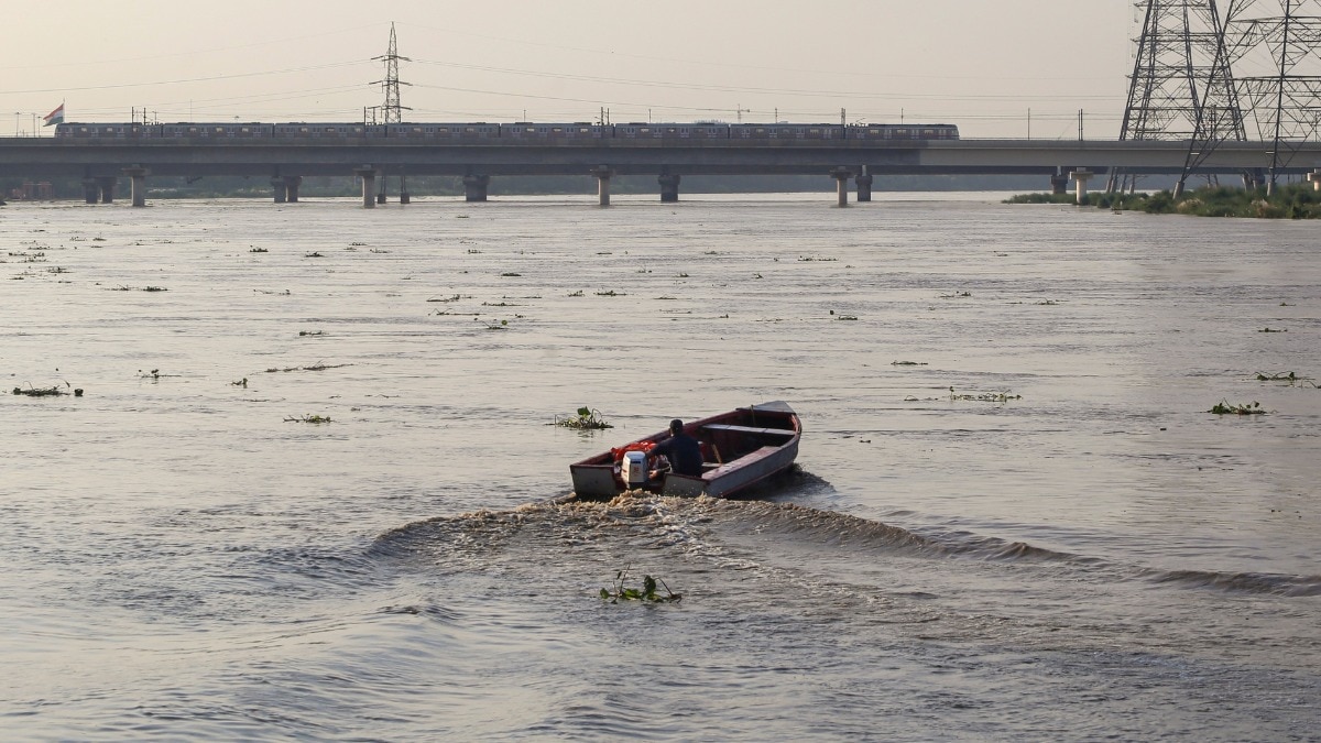 दिल्ली में उफनती यमुना नदी में मोटरबोट चलाता एक आदमी. (Photo: PTI)
