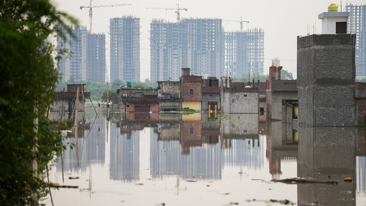 यमुना नदी के खतरे के निशान से ऊपर बह रही है. तस्वीर दिल्ली के जैतपुर यमुना पुश्ता की है, जहां कि इमारतें पानी में डूबी हुई दिख रही हैं. (Photo: PTI)