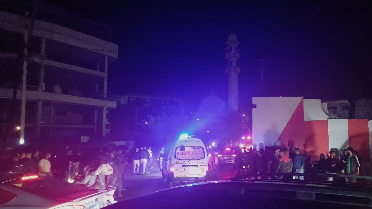 People gathering next of an ambulance as it enters the Ein el-Hilweh refugee camp in the southern port city of Sidon, Lebanon, Tuesday, Nov. 18, 2025. (AP Photo/Mohammed Zaatari)
