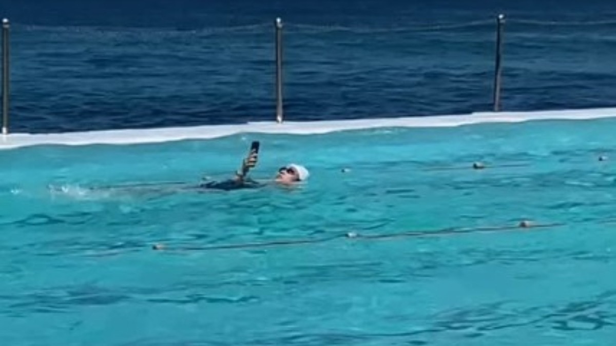 woman-using-phone-while-swimming-in-pool-australia-viral-video-life