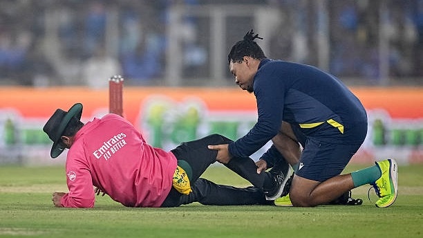 A field umpire (L) reacts after being hit by the ball as a physio attends him during the fifth Twenty20 international cricket match between India and South Africa at the Narendra Modi Stadium in Ahmedabad on December 19, 2025