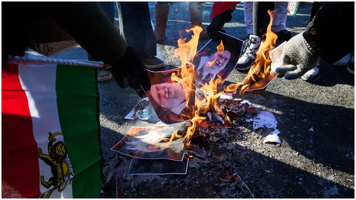 Protesters burn pictures of Iranian Supreme Leader Ayatollah Ali Khamenei as they march in support of regime change in Iran during a protest in Toronto