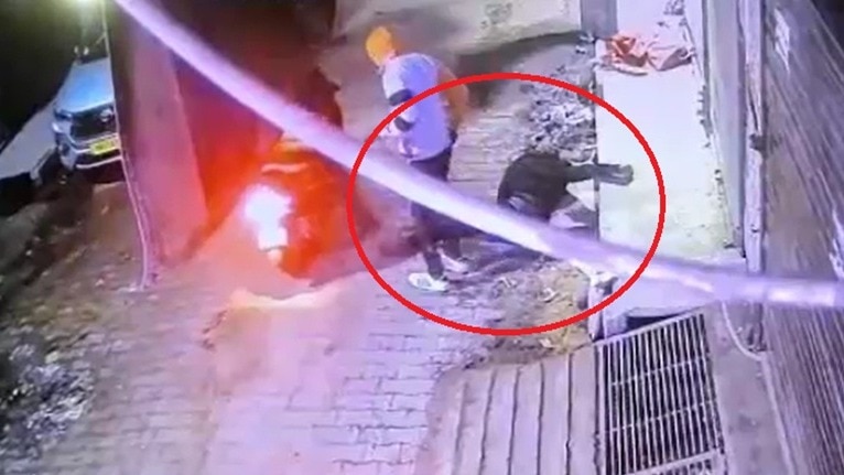 जमीन पर गिरे युवक का फोन चुराकर भागते स्कूटी सवार. (Photo: Screengrab)