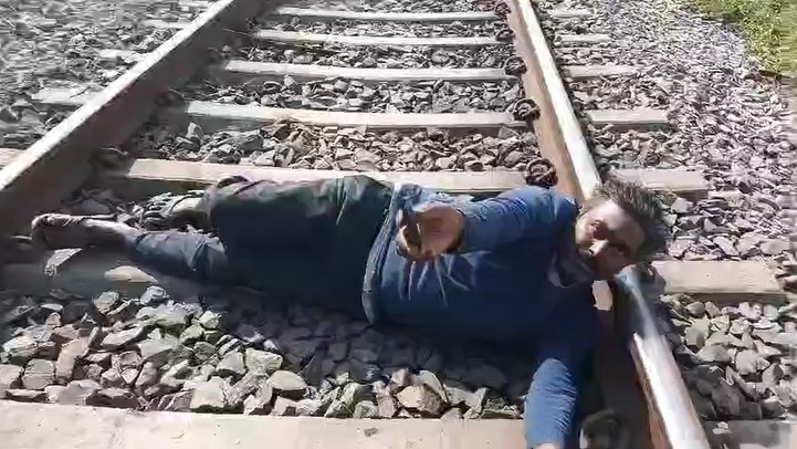 ट्रैक पर लेटे युवक को लोगों ने बचाया.(Photo: Screengrab)