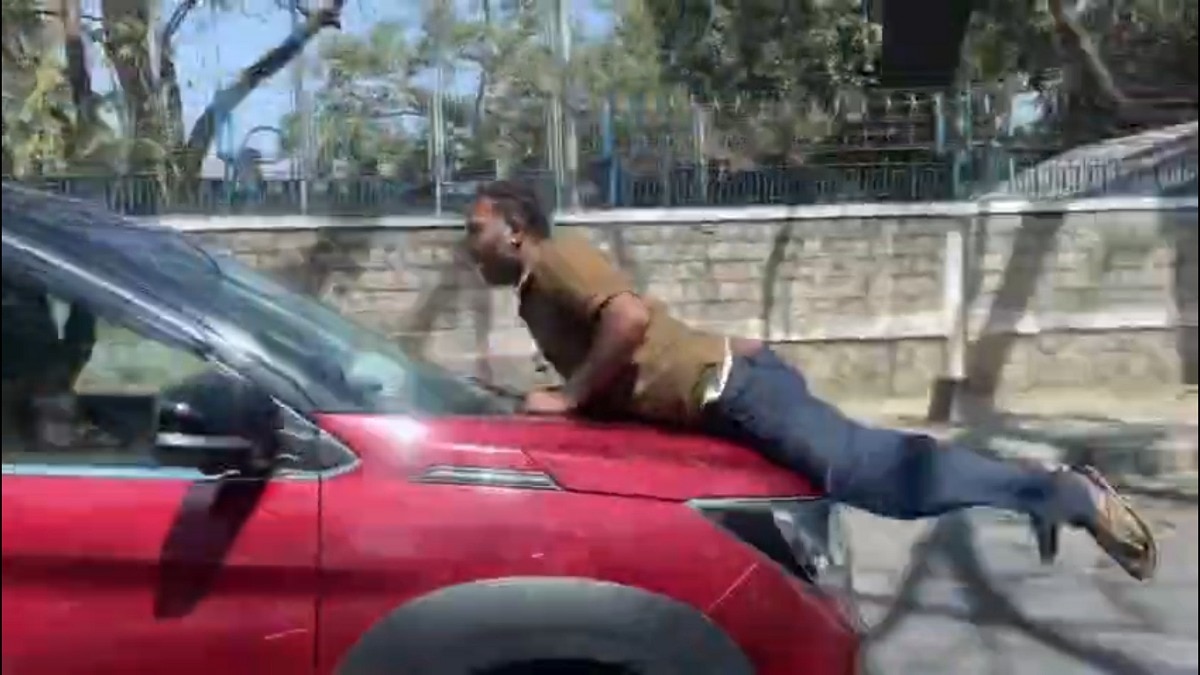 तेज रफ्तार कार के बोनट पर व्यक्ति लटका रहा. (Photo: Screengrab)