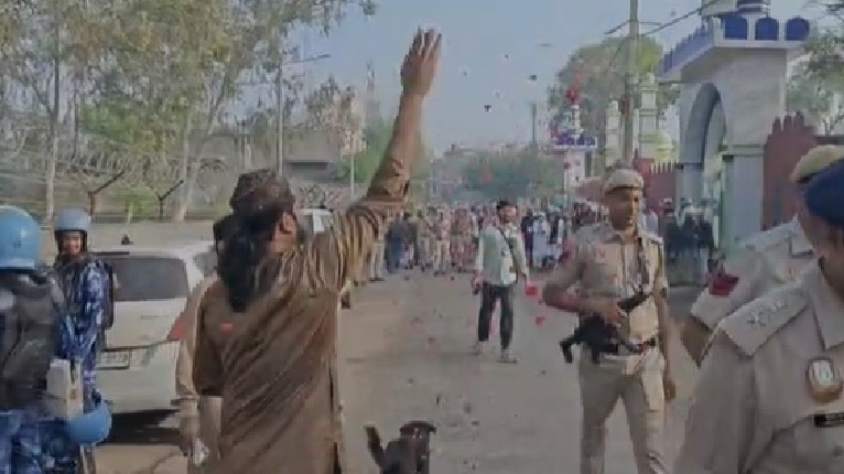 सुरक्षा में तैनात जवानों पर फूल बरसाते ईदगाह कमेटी के लोग. (Photo: Screengrab) 