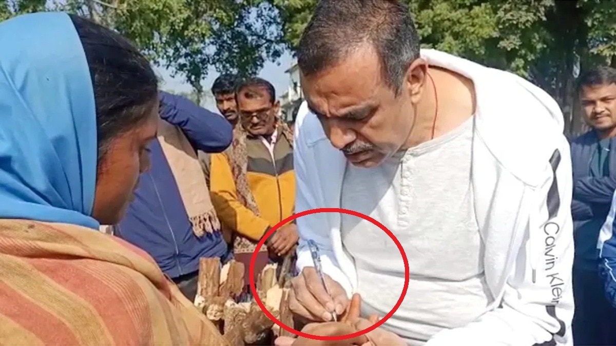 महिला के हाथ पर लिखा अपना मोबाइल नंबर लिखते IAS अफसर विकास मिश्रा.(Photo:ITG)