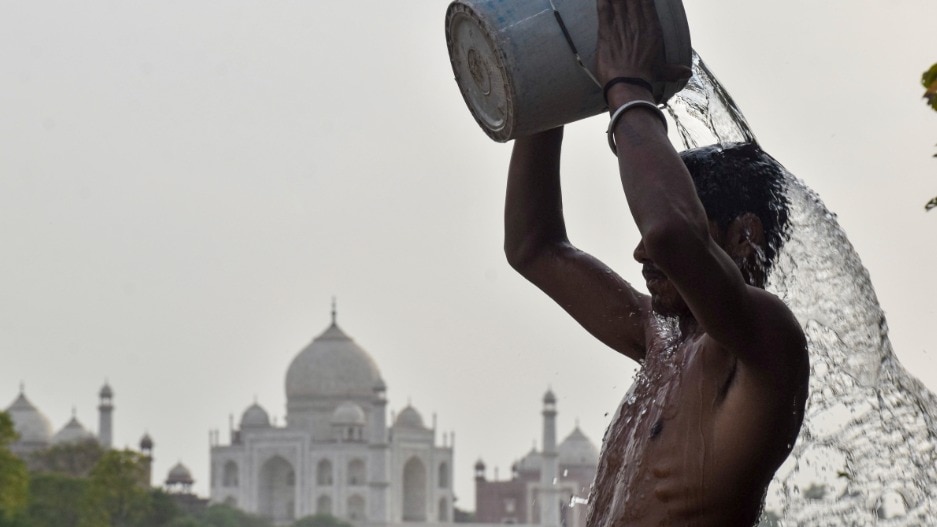 A man pours a bucket of water to beat the heat on a hot summer day, near Taj Mahal (PTI Photo)