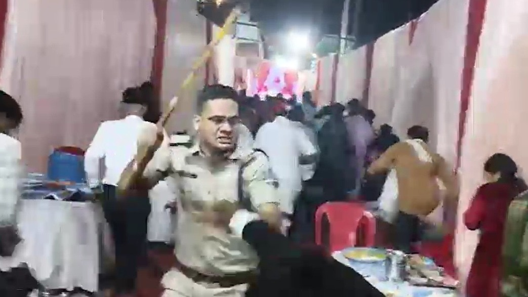 बारातियों की पिटाई करता एक पुलिसकर्मी. (Photo: Screengrab)