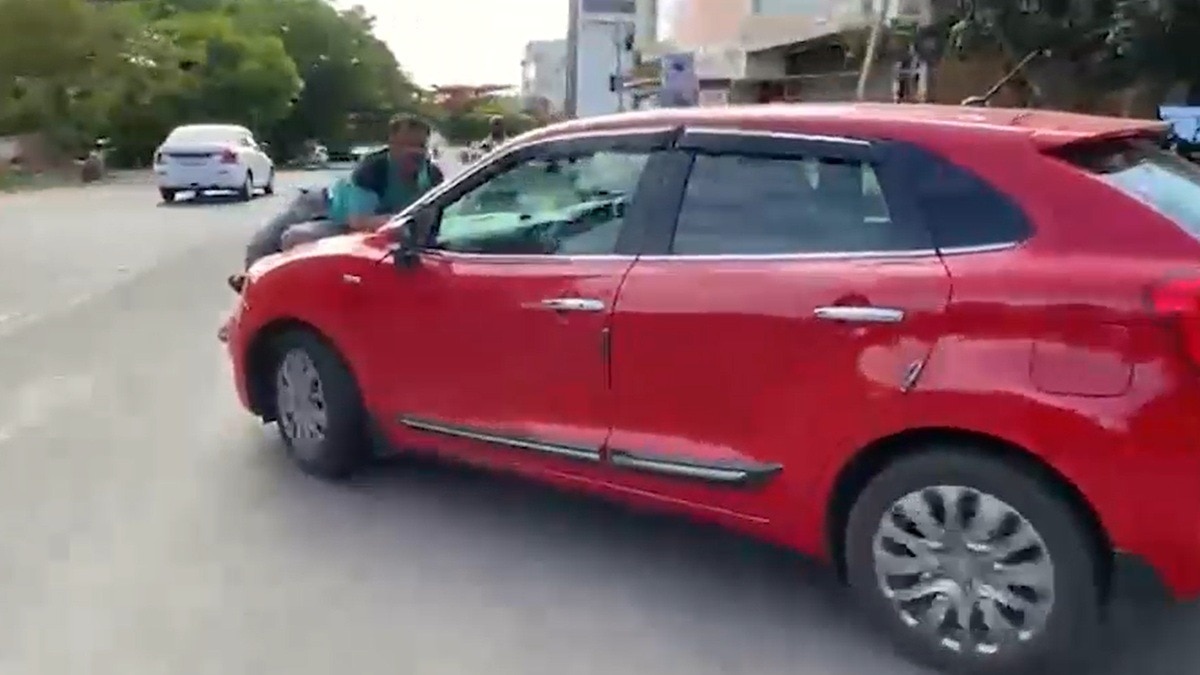 चलती कार के बोनट पर लटका युवक. (Photo: Screengrab)