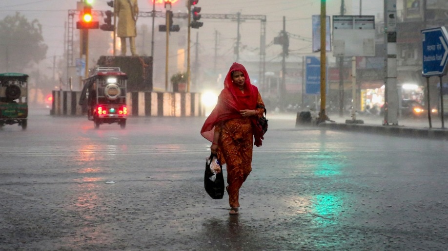 A woman covers herself during the rainfall (PTI Photo)