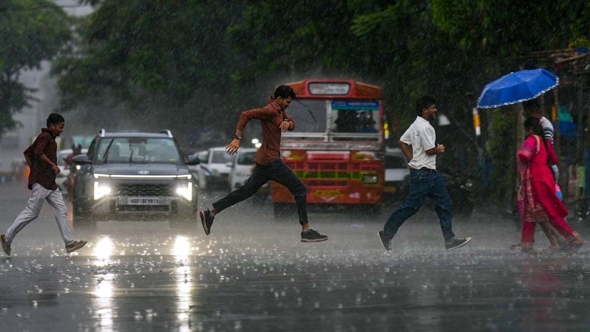 कोलकाता में बारिश के दौरान सड़क पार करते लोग. (Photo: PTI)