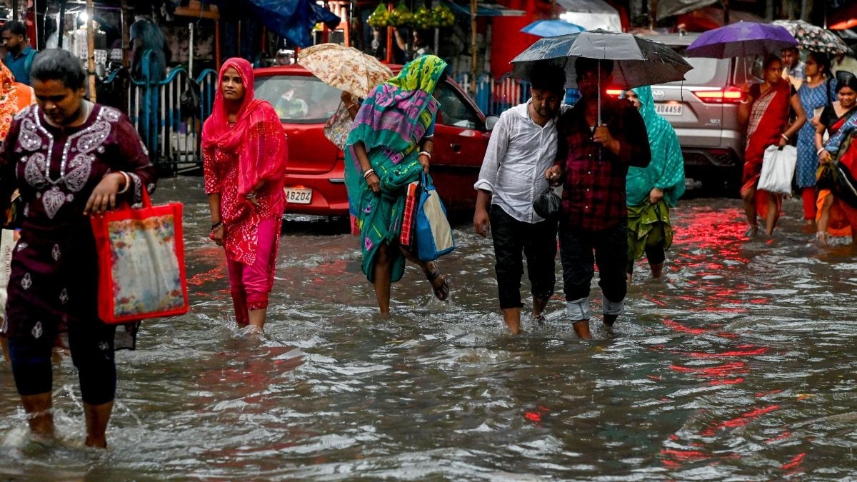 मानसून की बारिश के बीच जलभराव वाली सड़क से गुजरते लोग. (Photo: PTI)