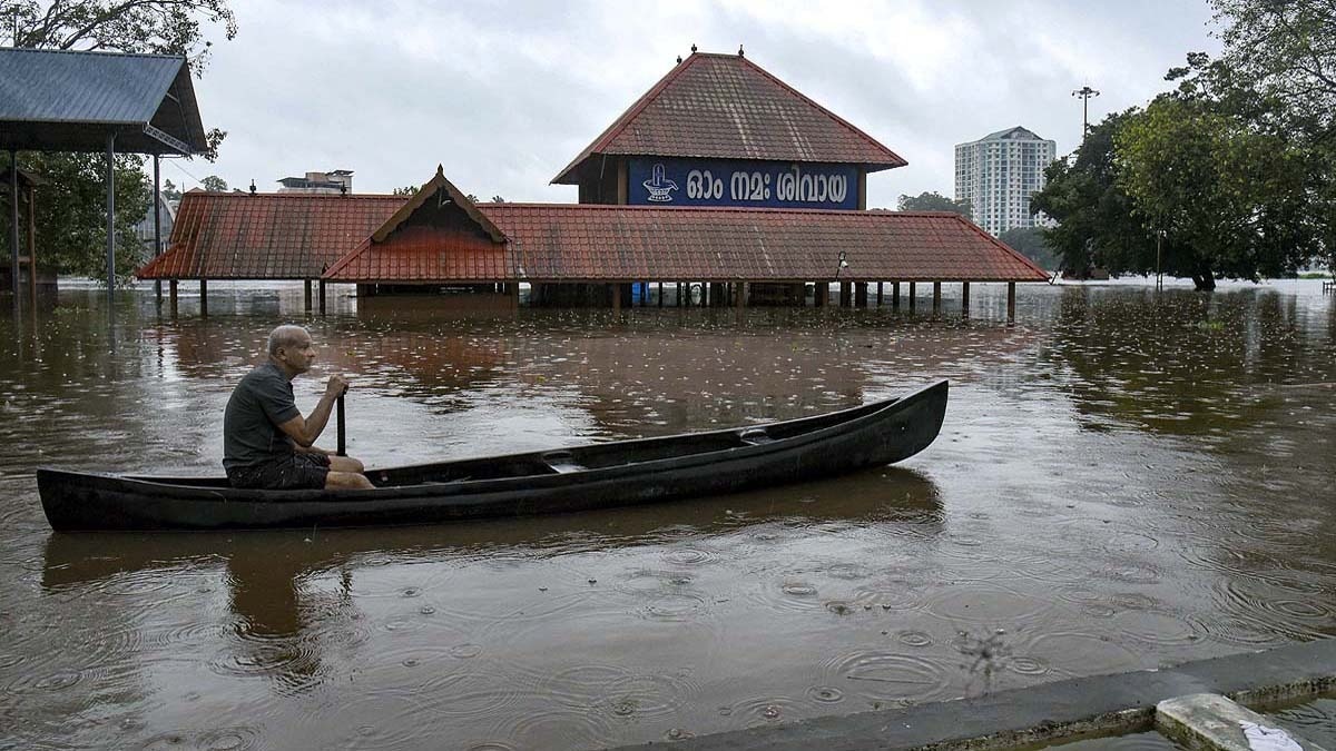 केरल के कोच्चि में भारी बारिश के बाद जमा पानी में नाव चलाता व्यक्ति. (Photo: PTI)