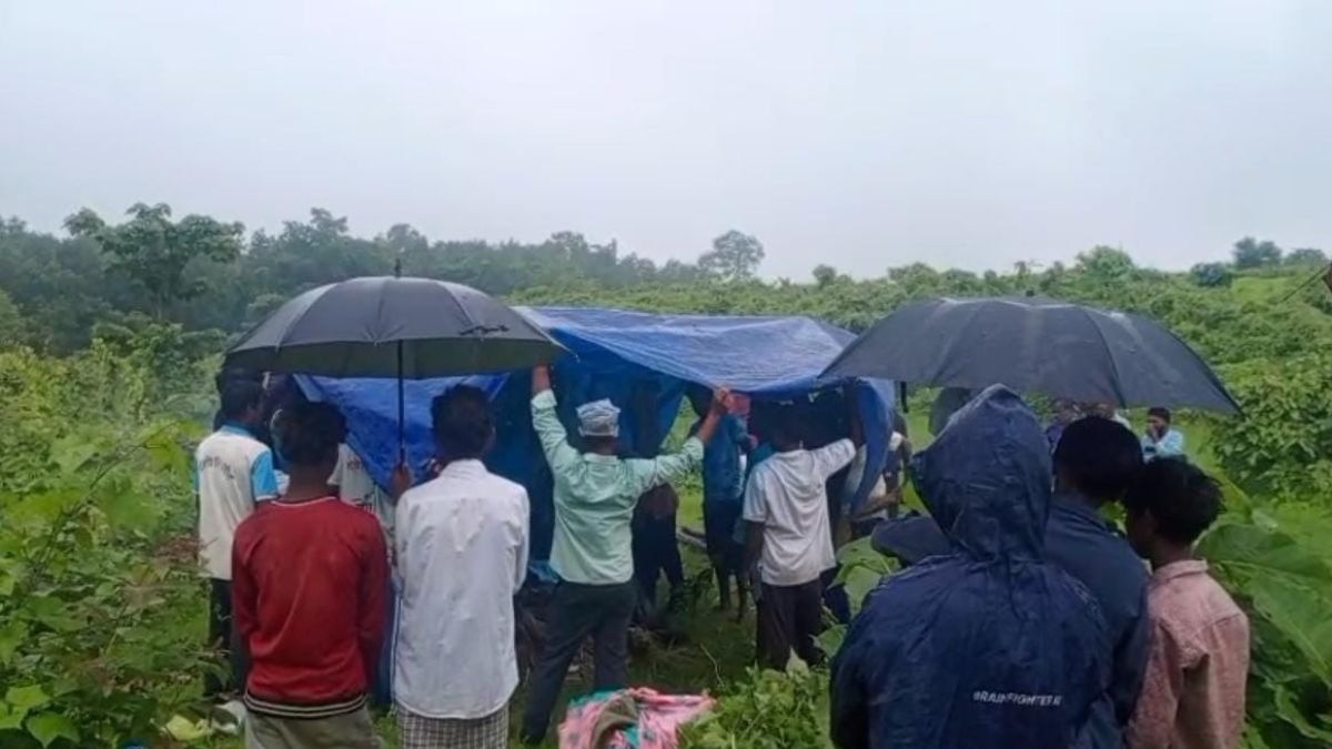 छाता- तिरपाल लगा कर बारिश में अंतिम संस्कार करने को मजबूर लोग. (Photo- Mithilesh Gupta/ ITG)