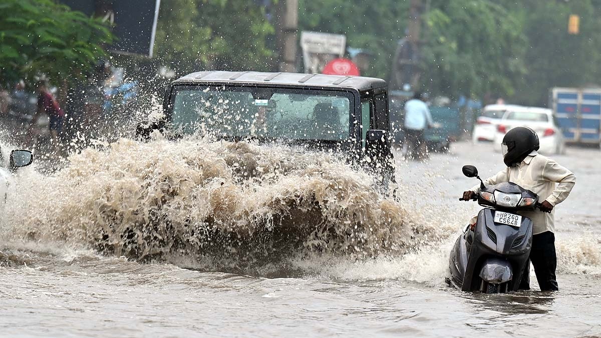 गुरुग्राम में बारिश के दौरान पानी से भरे सड़क से गुजरती गाड़ियां. (Photo: PTI)