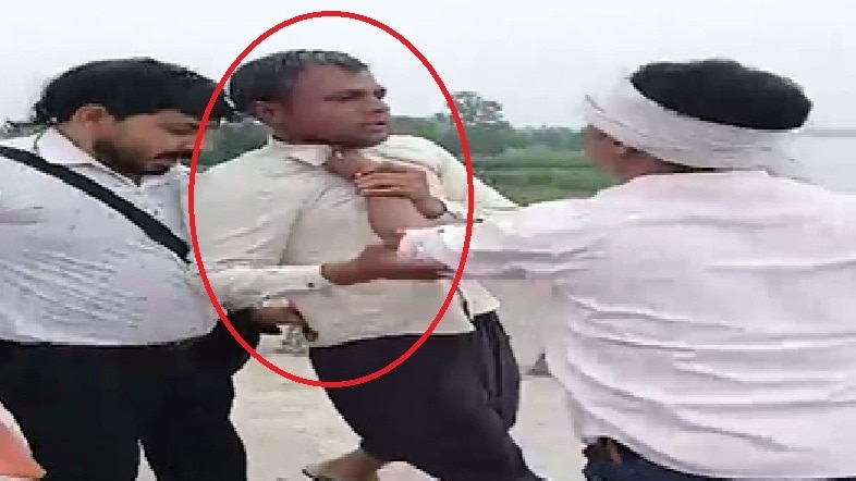 बेटी को फेंकने के बाद आरोपी की पिटाई करते लोग. (Photo: Screengrabs)