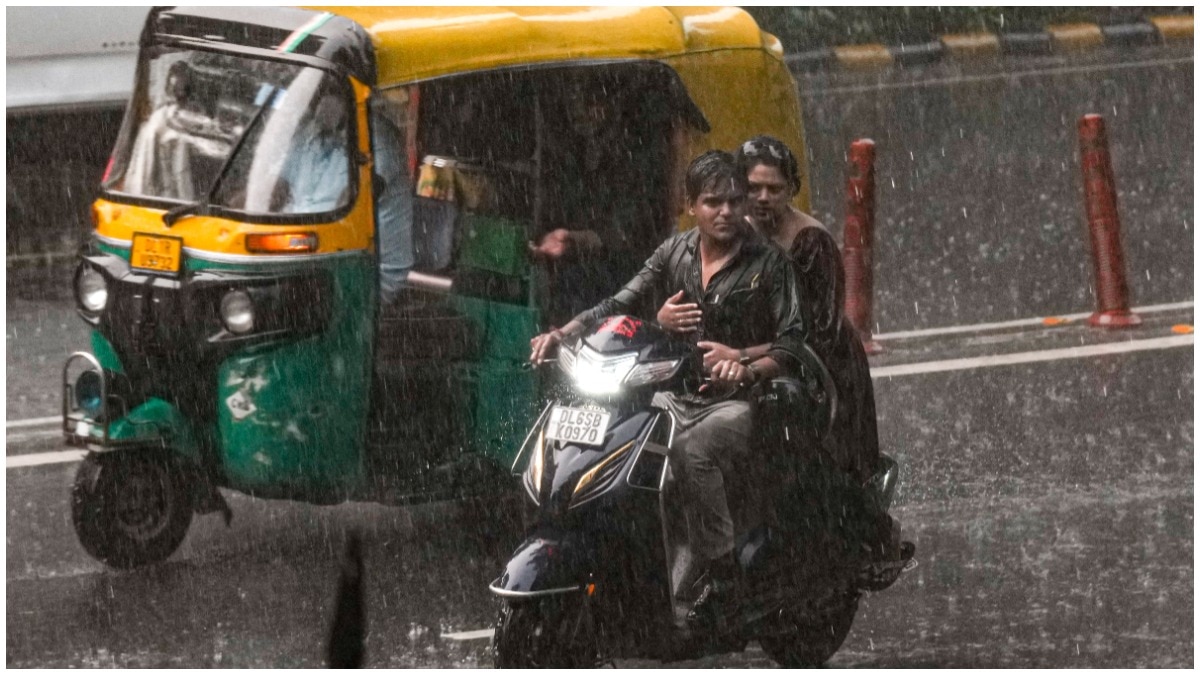 दिल्ली में भारी बारिश के बीच आते-जाते लोग. (Photo: PTI)