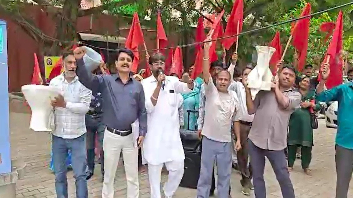 टॉयलेट सीट लेकर प्रदर्शन करते नगर निगम के कर्मचारी. (photo: Screengrabs)