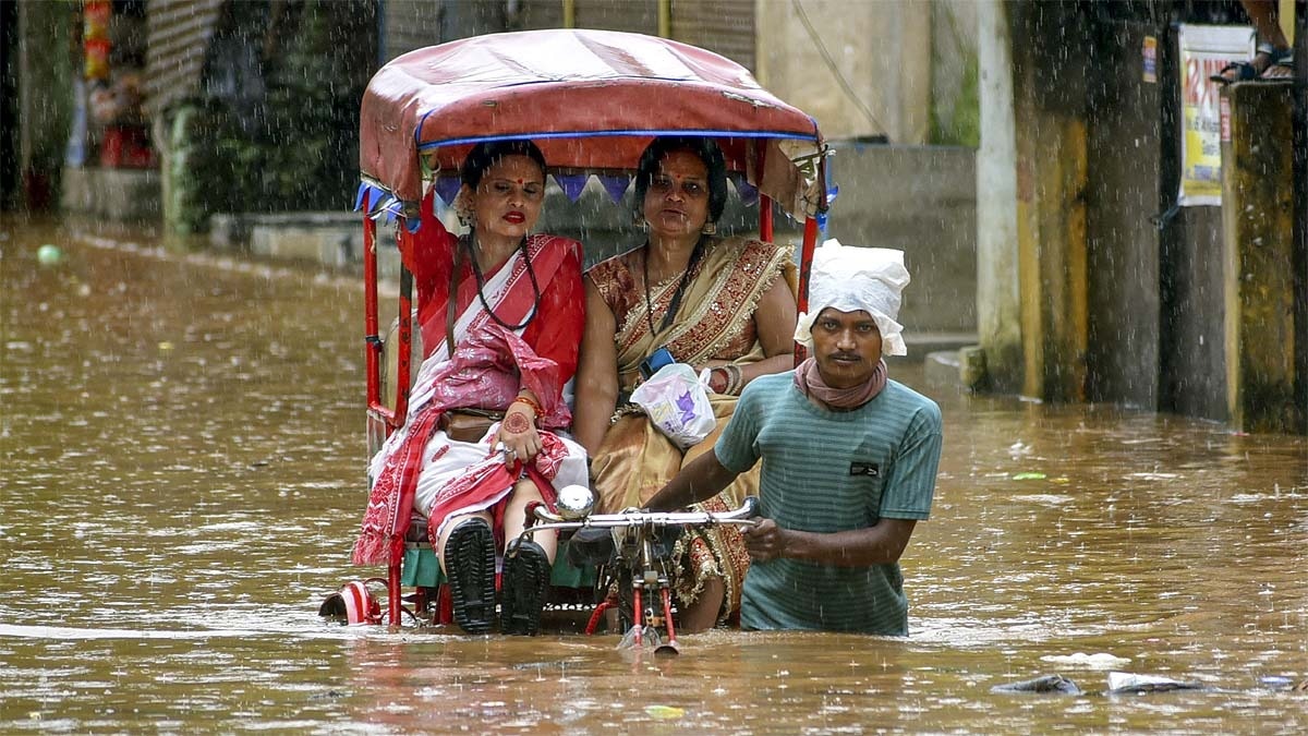 गुवाहाटी में बारिश के बीच गुजरते लोग. (Photo: PTI)