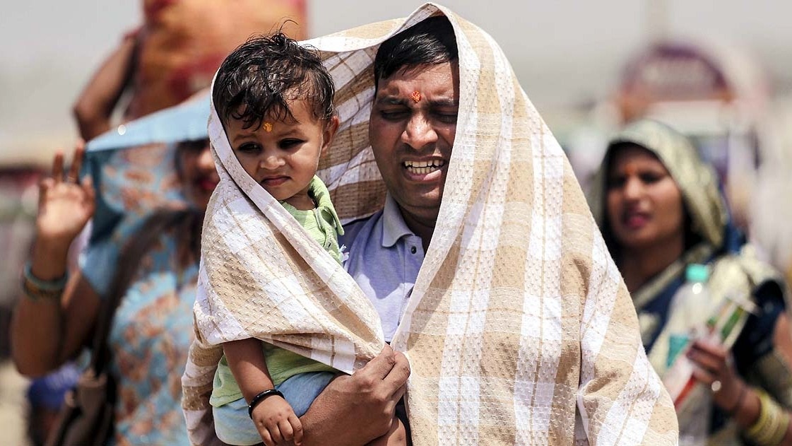 प्रयागराज में गर्मी से बचने के बच्चे और खुद को तौलिये से ढका व्यक्ति. (File Photo: PTI)