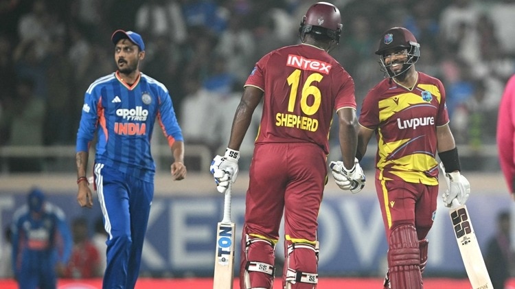 West Indies captain Shai Hope (R) shakes hands with teammate Romario Shepherd (C)