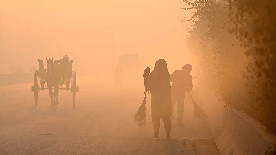 स्मोग से भरे लाहौर की सड़क पर काम करते सफाईकर्मी. (Photo: AFP)