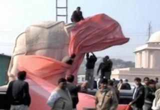 मायावती की मूर्तियों को ढकते लोग