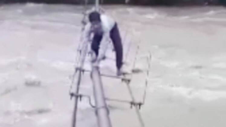 पाइप के सहारे उफनती नदी को पार करते स्कूली बच्चे