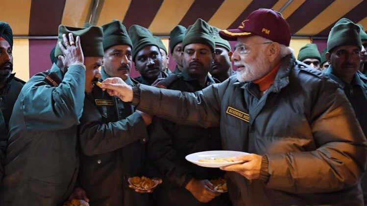 प्रधानमंत्री नरेंद्र मोदी जवानों को मिठाई खिलाते हुए (फोटो-PIB)