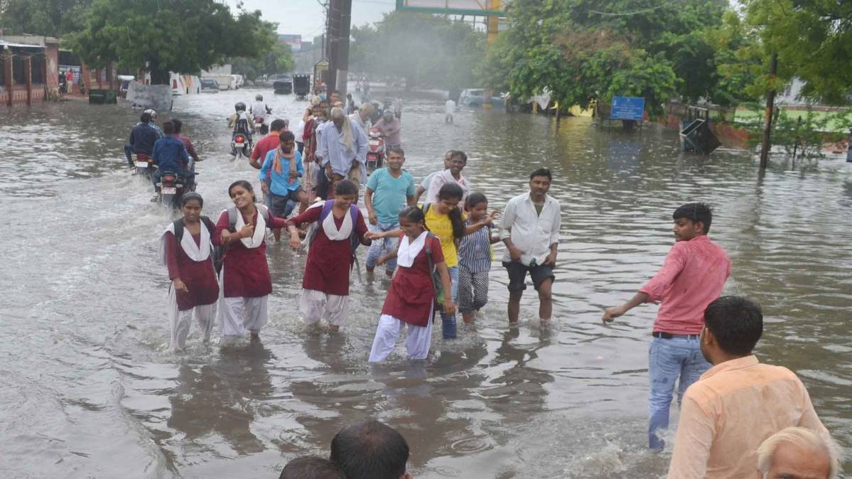 रास्ते में भरे पानी से होकर स्कूल जाते विद्यार्थी (फाइल फोटो-IANS)