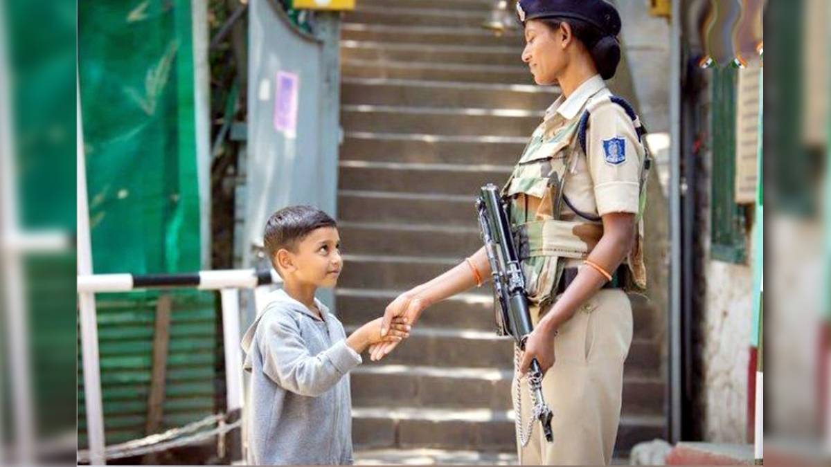 कश्‍मीर में बच्‍चे से हाथ मिलाती महिला CRPF जवान(फोटो-IANS)