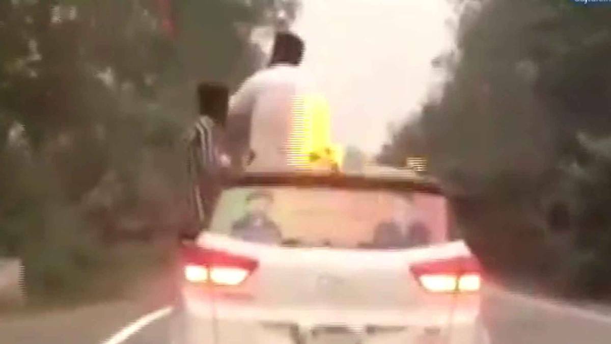 कार की छत पर दारू पीते हुए शख्स