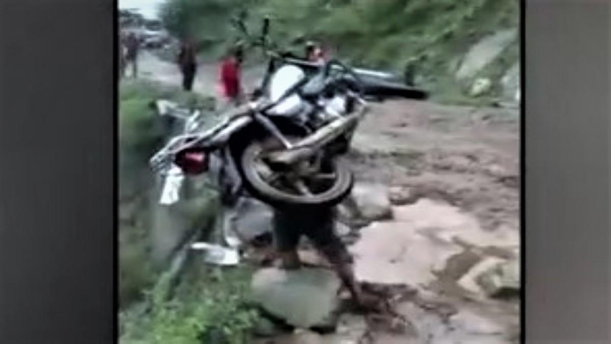 Local carrying bike on shoulders amid flood in Chamba, Himachal Pradesh