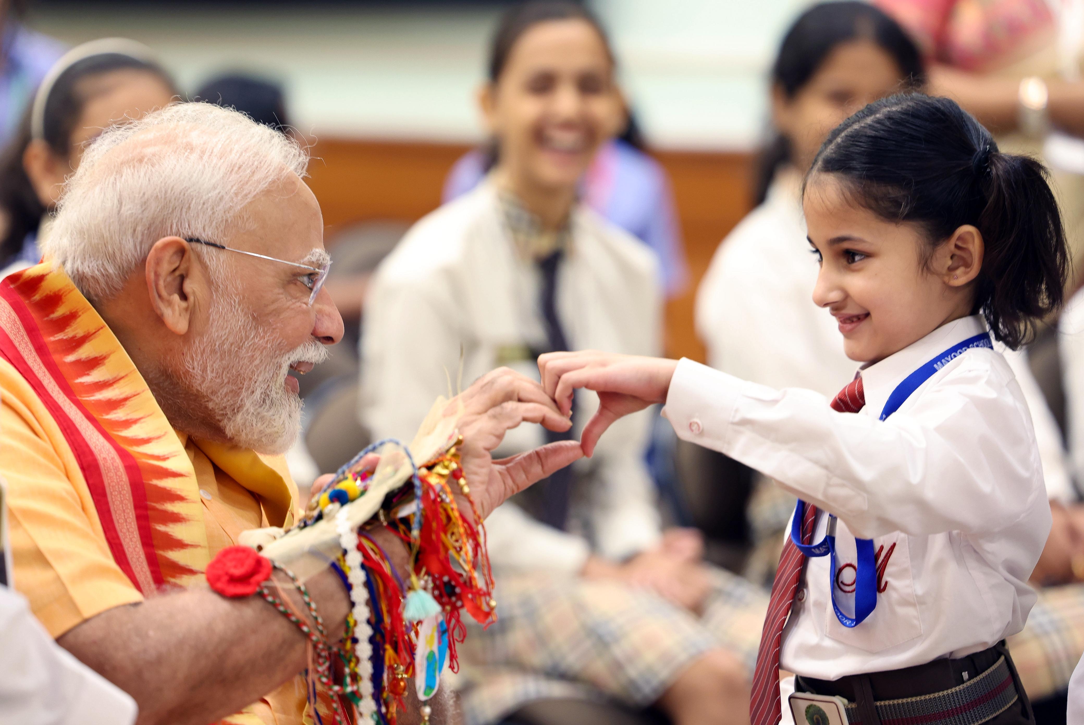 Girl tying Rakhi to PM Modi