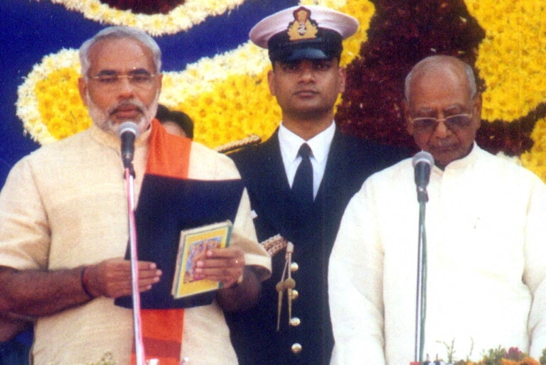 2002 के चुनाव में भाजपा ने नरेंद्र मोदी के नेतृत्व में बहुमत वाली सरकार बनाई. शपथ लेने पहुंचे मोदी के हाथों में भगवत गीता थी. (Photo- AFP)