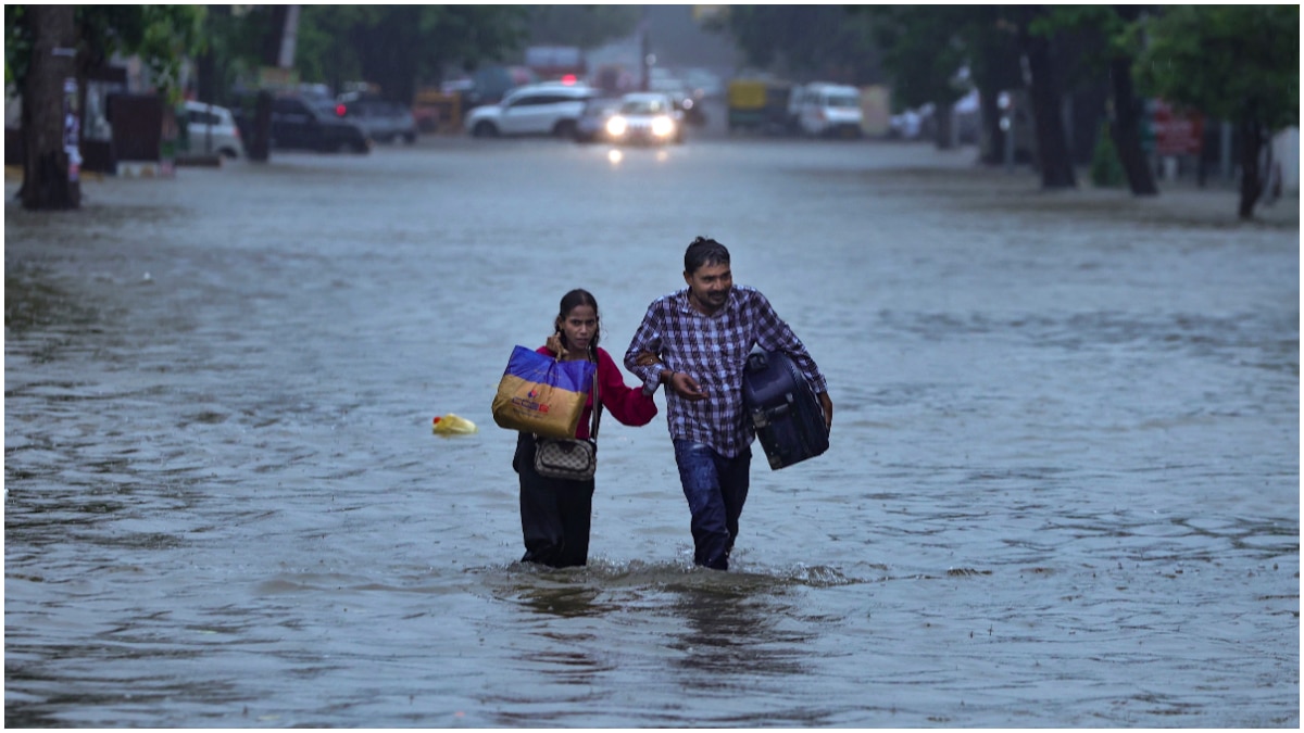 Commuters wade through a waterlogged road following heavy rainfall, in Prayagraj Commuters wade through a waterlogged road following heavy rainfall, in Prayagraj