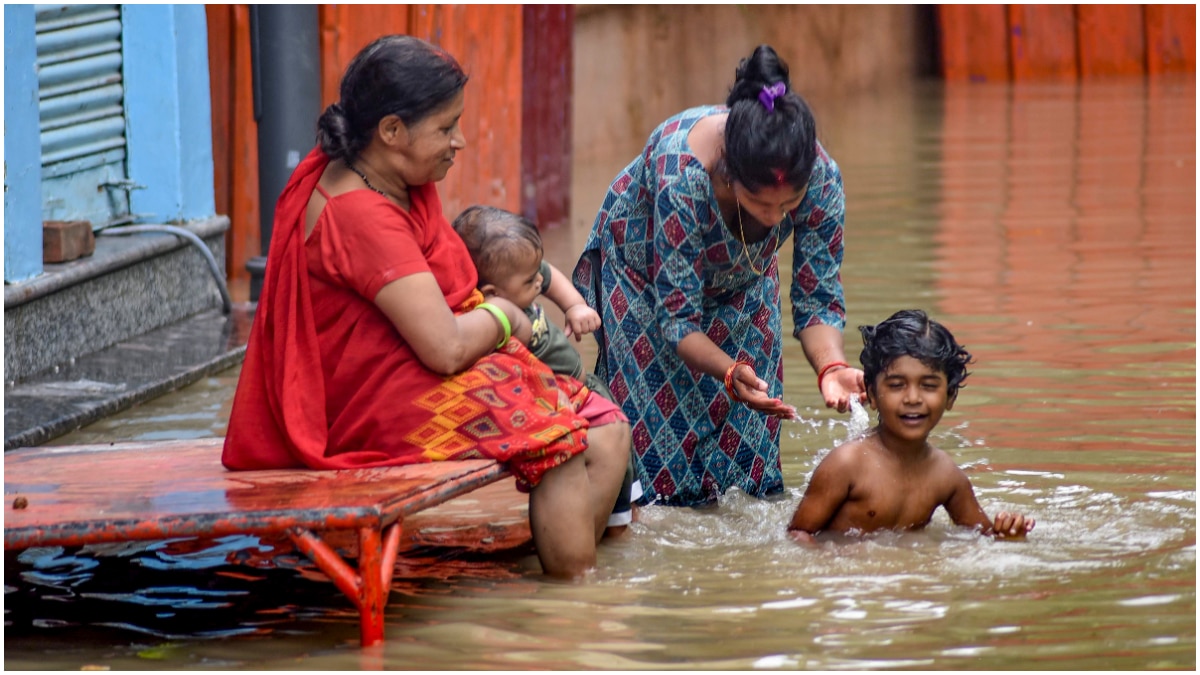 Family members look on as a boy plays in waterlogged grounds after heavy rains, near Assi Ghat in Varanasi Family members look on as a boy plays in waterlogged grounds after heavy rains, near Assi Ghat in Varanasi