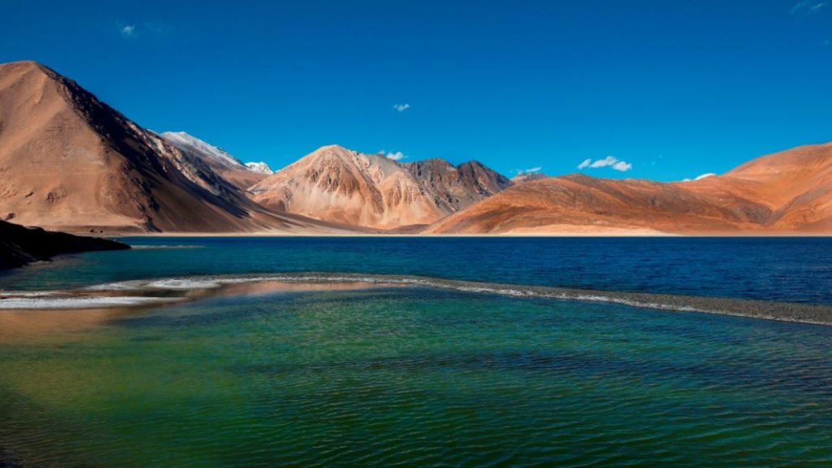 The changing hues of Pangong Lake amidst snow-capped mountains.