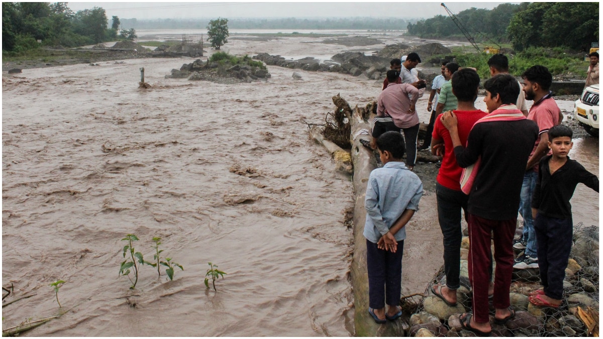 People gather near an overflowing causeway as the swollen Bin river flows following incessant heavy rainfall, in Rishikesh People gather near an overflowing causeway as the swollen Bin river flows following incessant heavy rainfall, in Rishikesh