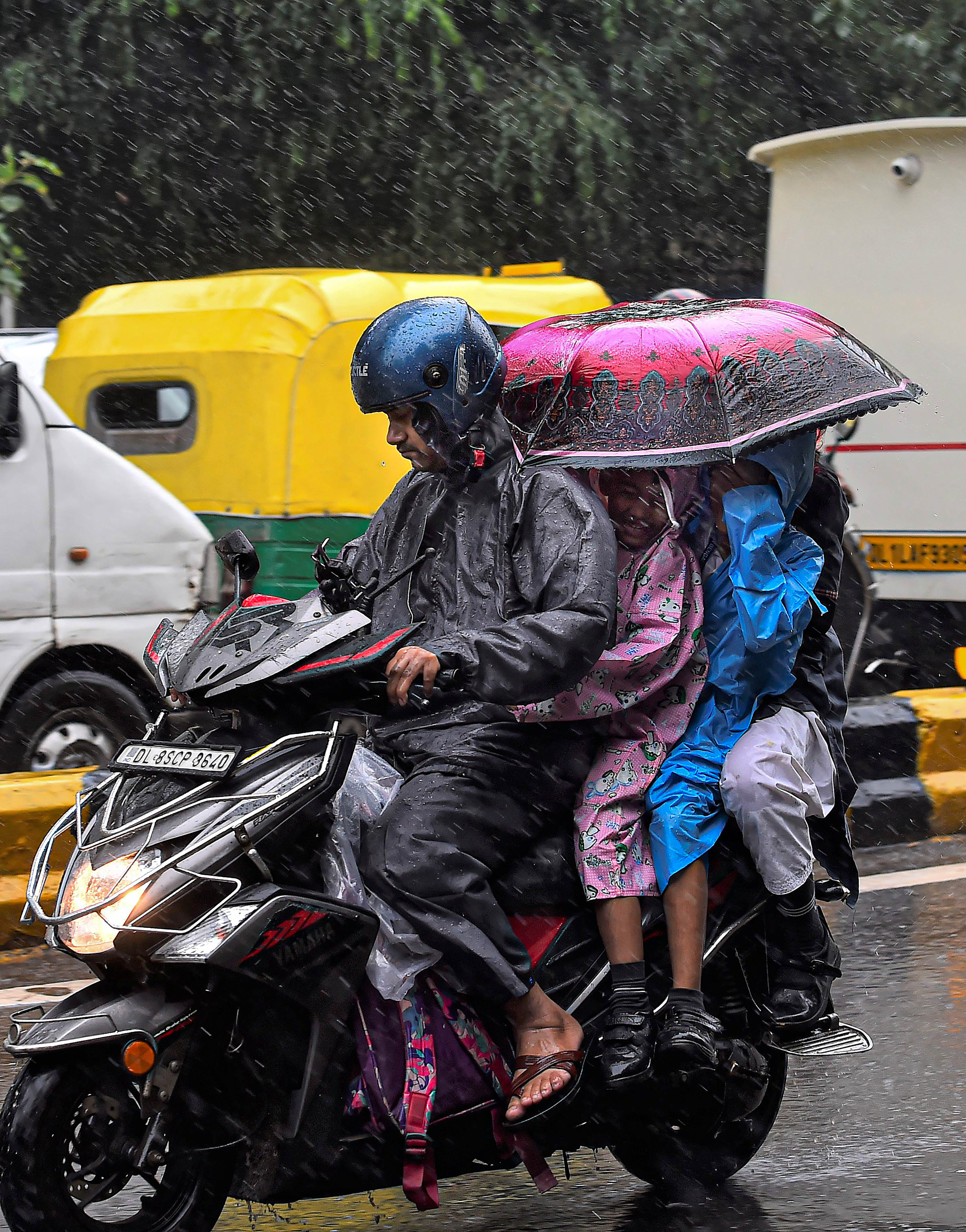 बारिश में बच्चों को घर ले जाते हुए (फोटो- पीटीआई)