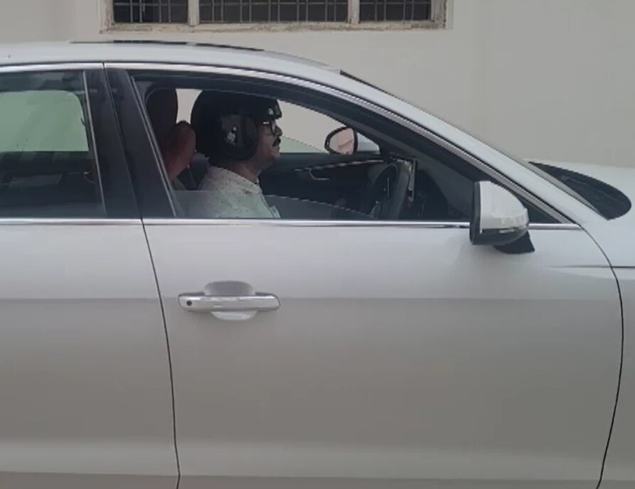 हेलमेट पहनकर कार चलाता शख्स