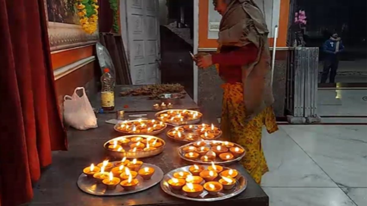 मंदिर में दीप जलाते श्रद्धालु.