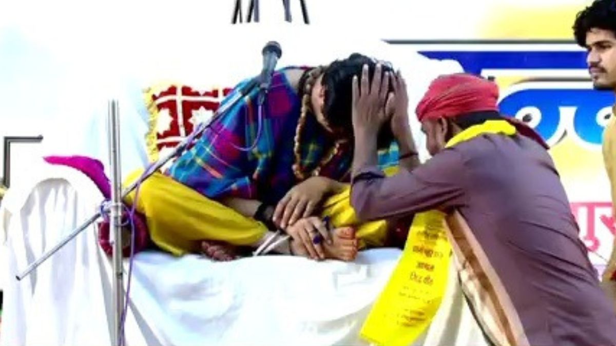 Dhirendra Shastri sitting on the stage wearing a helmet.