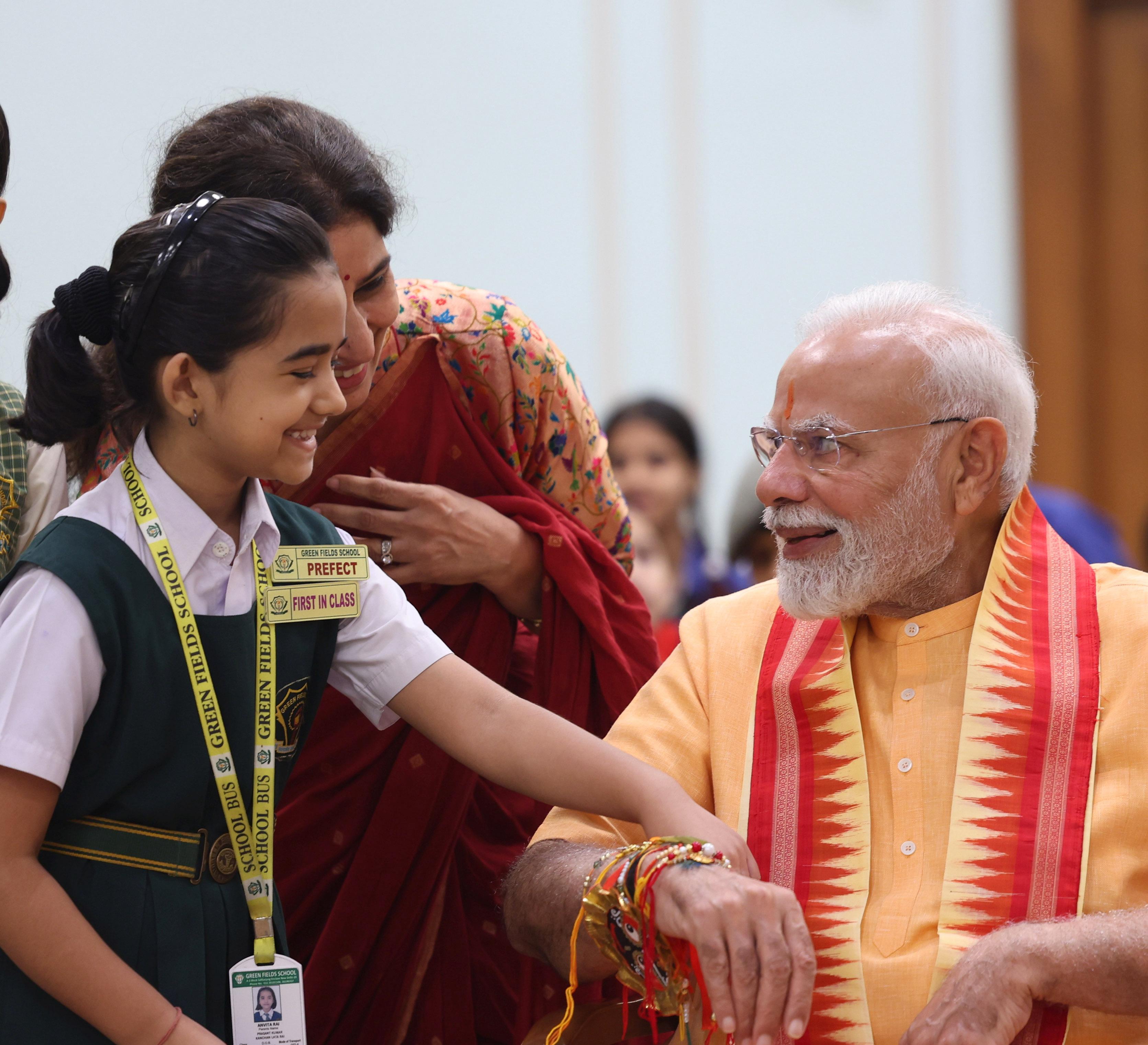 Girl tying Rakhi to PM Modi