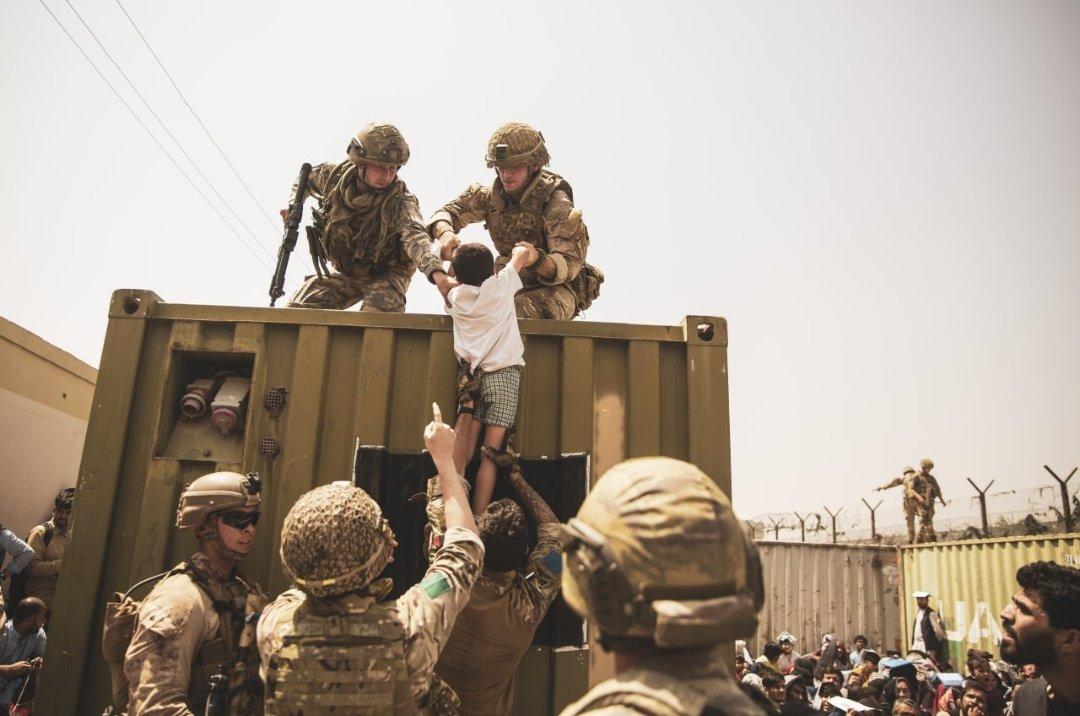 ट्रक पर बच्चे को चढ़ाने में मदद करते अमेरिकी सैनिक