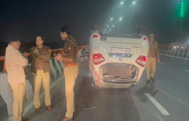पलटी हुई कार और मौके पर मौजूद नोएडा पुलिस.